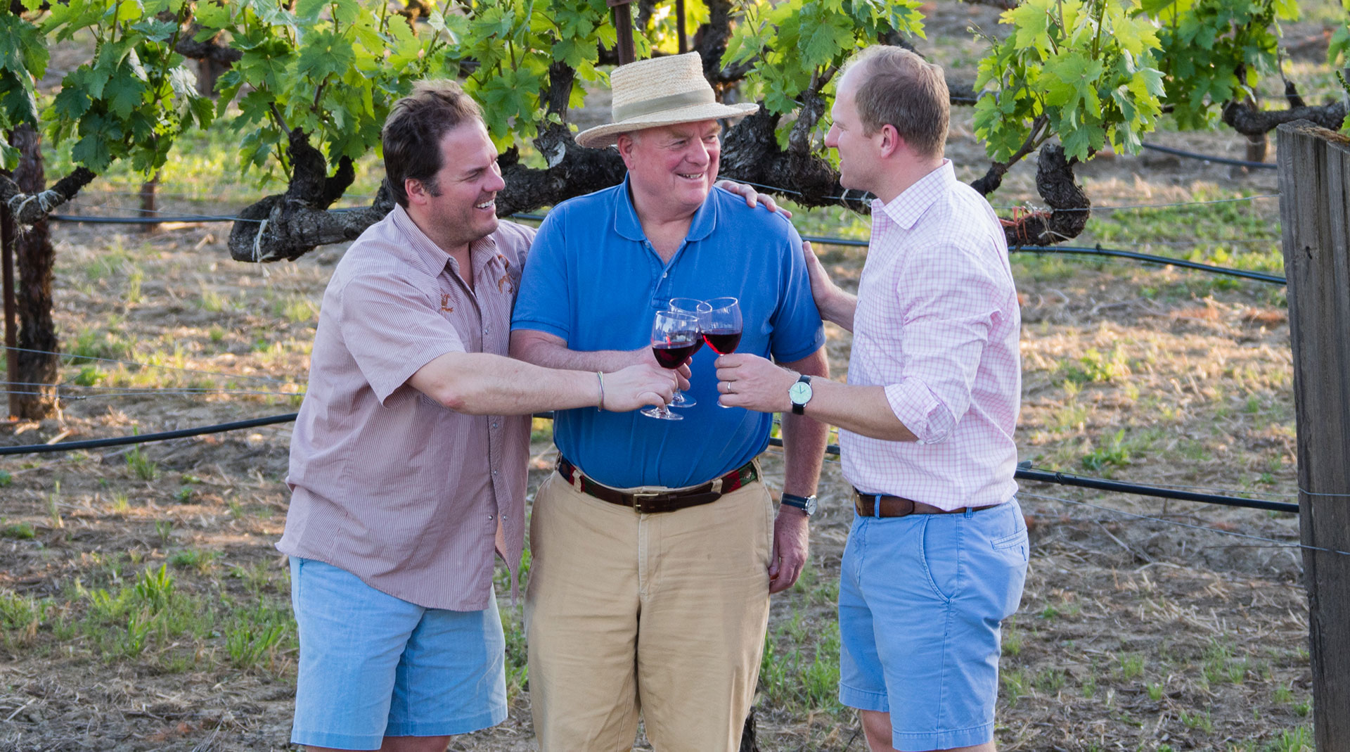 Joe Donelan toasting wine glasses in vineyard with sons.