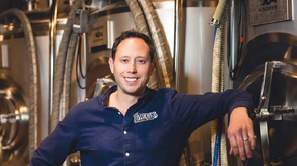 John Rubbo posing in his beer factory with a Yonkers Brewery shirt.