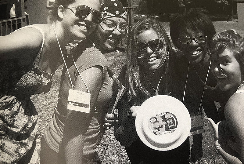 Women smile and pose with their frisbee.