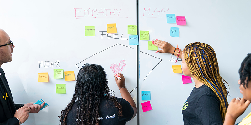 Chrisoph Winkler and students work on a white board together.