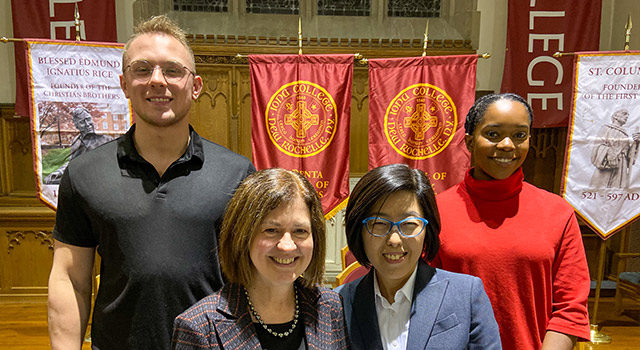 Faculty and students pose in front of banners to celebrate the induction of students to the national honors society.