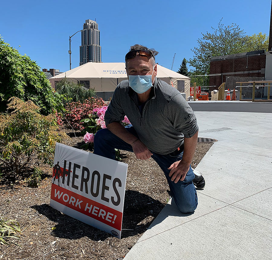 Louis Cordasco poses with a sign that says Heroes work here.