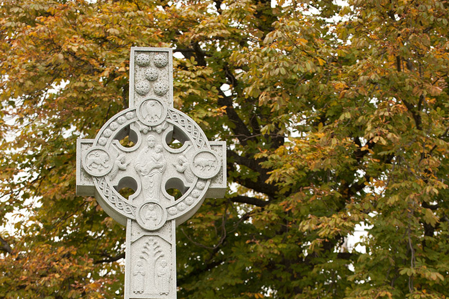 Iona College's Celtic Cross with an autumn tree in the background.