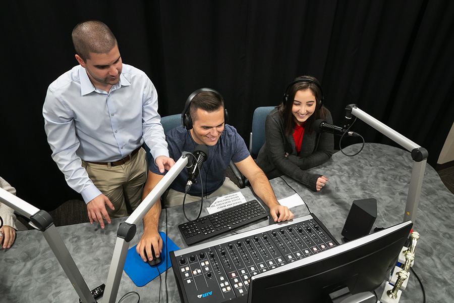 Joe teaches students how to use the podcast equipment in the media studio.
