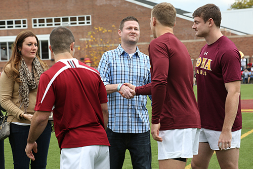 Pat Quinn shakes hands with the rugby team at homecoming.