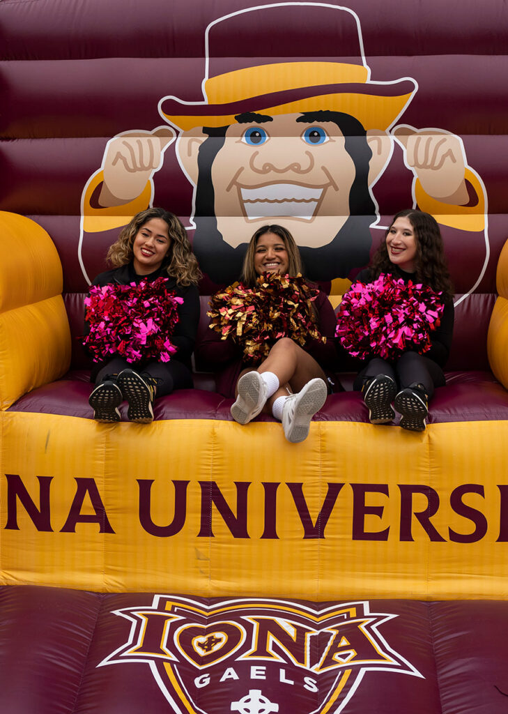 Three members of the cheer team sit on the inflatable Killian chair.