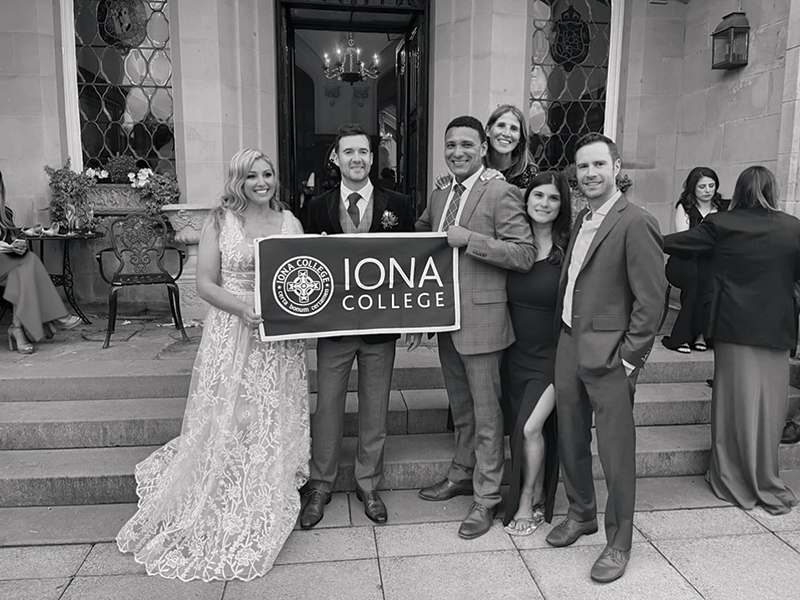 Four Iona students hold an Iona college flag at their wedding.