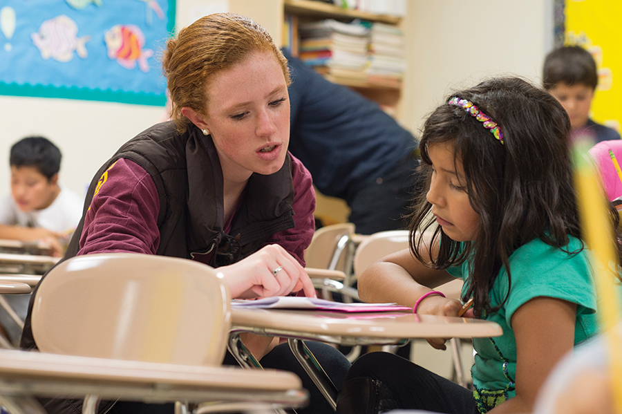 An Iona Education student teaches reading to a young learner.